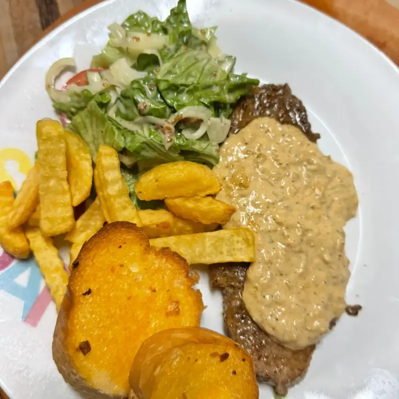 Beef steak with creamy pepper sauce, salad and french fries