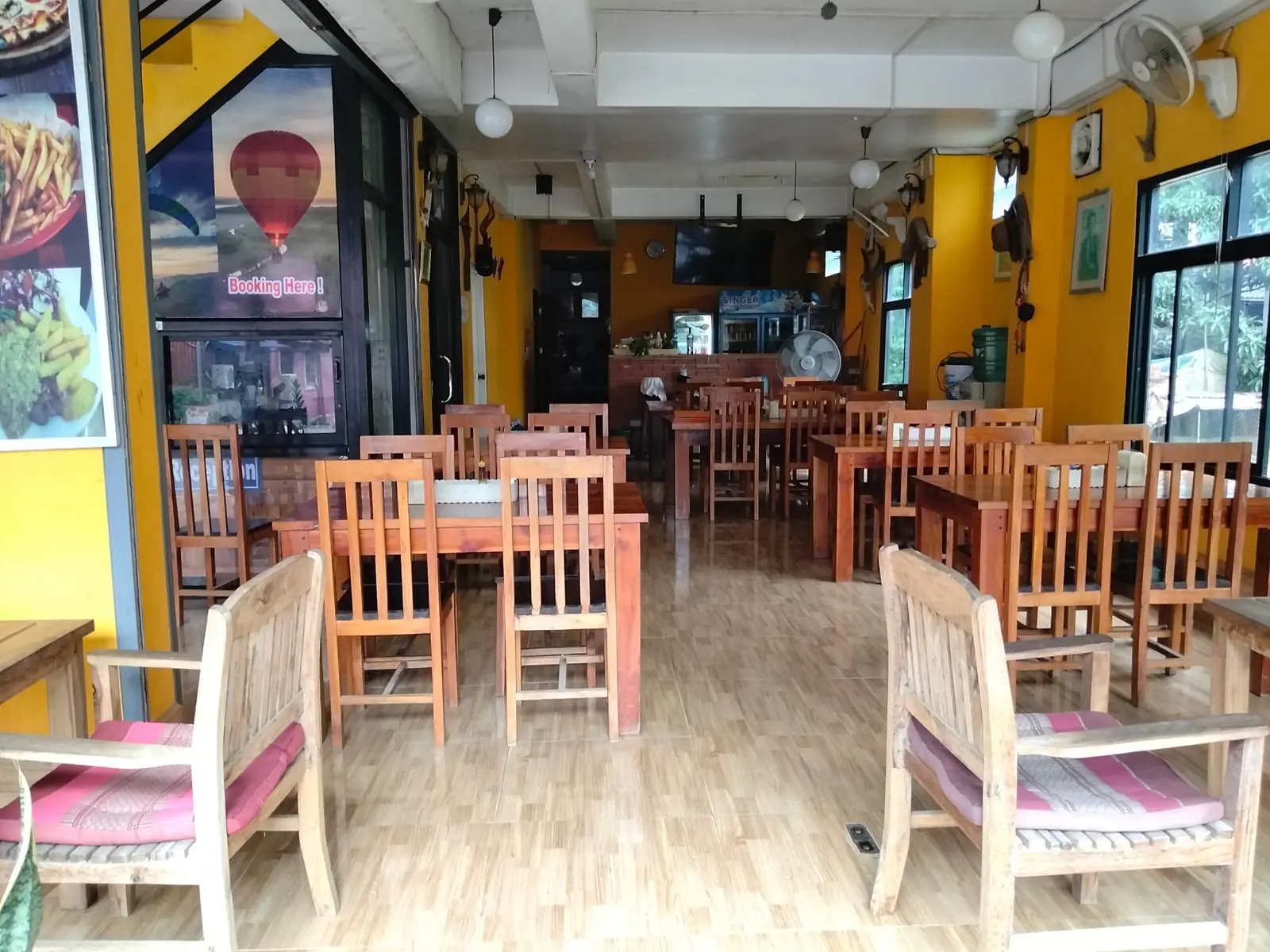 Inside the Vang Vieng Sunset restaurant — wooden tables and warm yellow walls