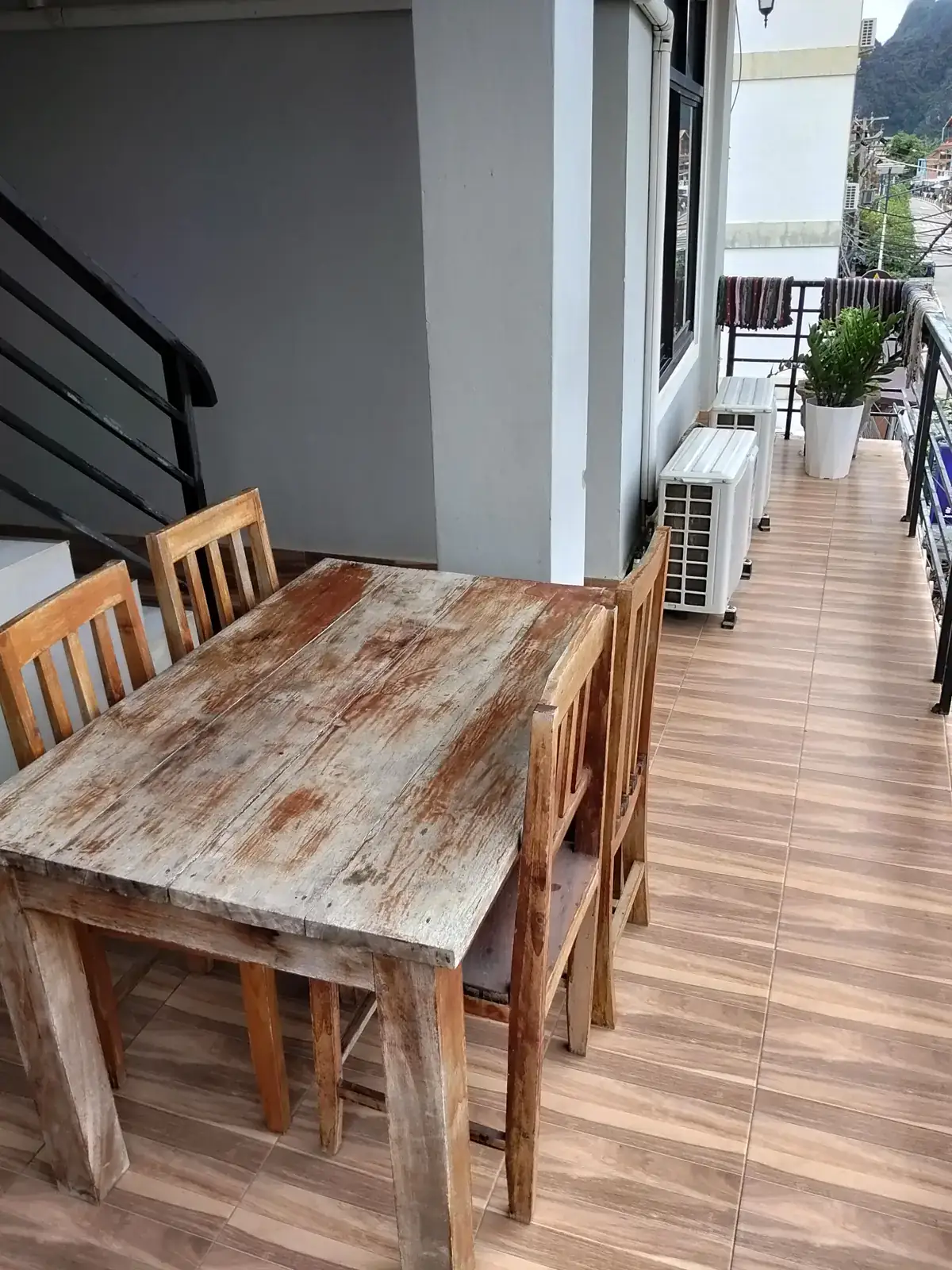 Wooden table and chairs on the terrace at Vang Vieng Sunset Guesthouse, with mountain views behind